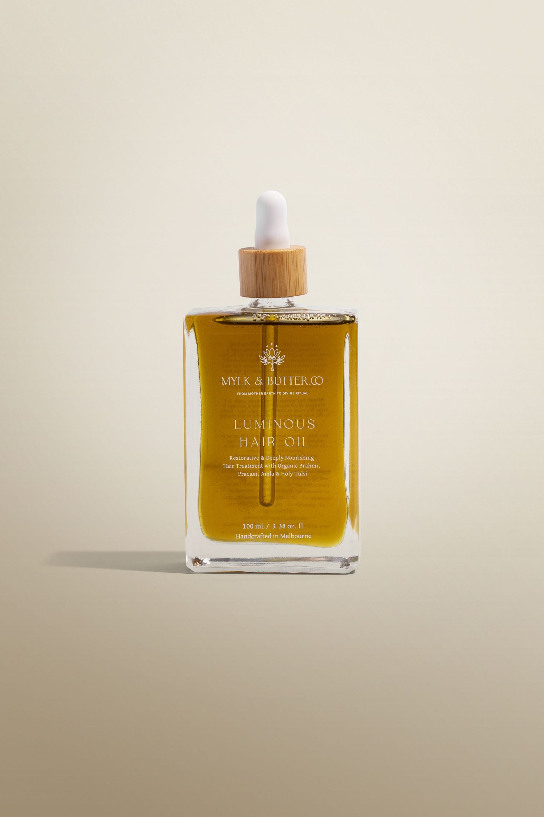 Bottle of Milk & Honey Luminous Hair Oil on a beige background